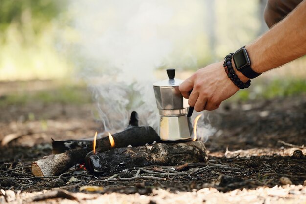 uomo che beve caffè nella foresta