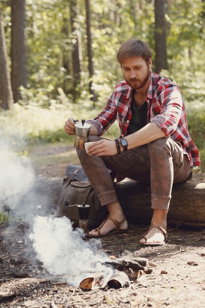 uomo che beve caffè nella foresta