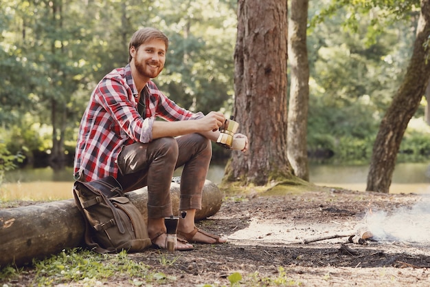 uomo che beve caffè nella foresta