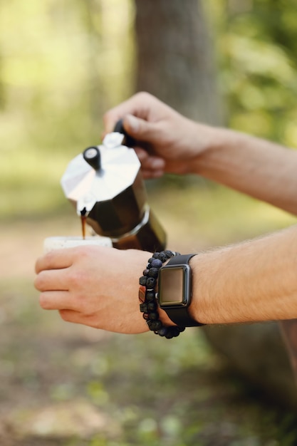 uomo che beve caffè nella foresta