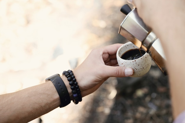 uomo che beve caffè nella foresta