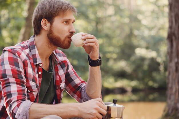 uomo che beve caffè nella foresta