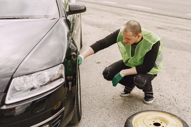 Uomo che cambia ruota rotta sull'automobile