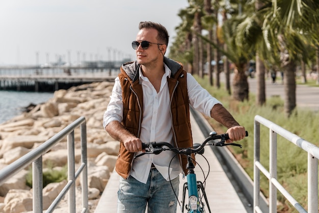 Uomo che cammina accanto alla sua bici all'aperto