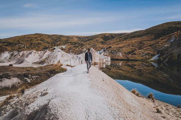 Uomo che cammina vicino a Blue Lake Walk in Nuova Zelanda, circondato da montagne
