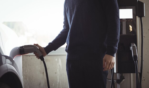 Uomo che carica auto alla stazione di ricarica per veicoli elettrici