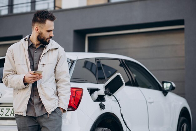 Uomo che carica un'auto elettrica vicino alla casa