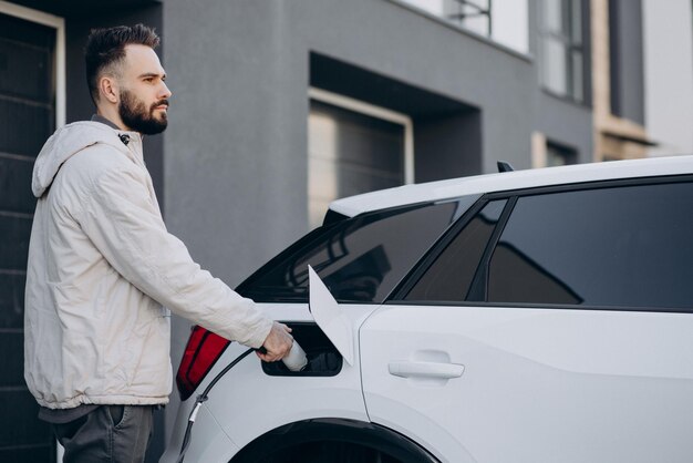 Uomo che carica un'auto elettrica vicino alla casa