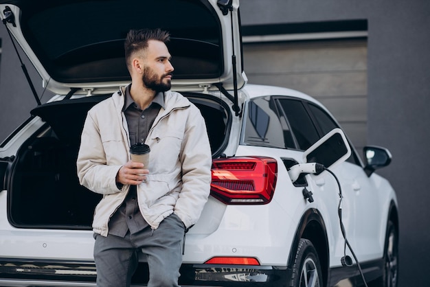 Uomo che carica un'auto elettrica vicino alla casa