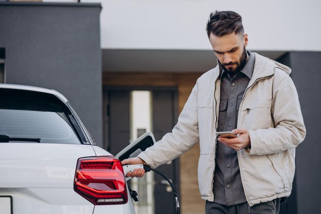 Uomo che carica un'auto elettrica vicino alla casa