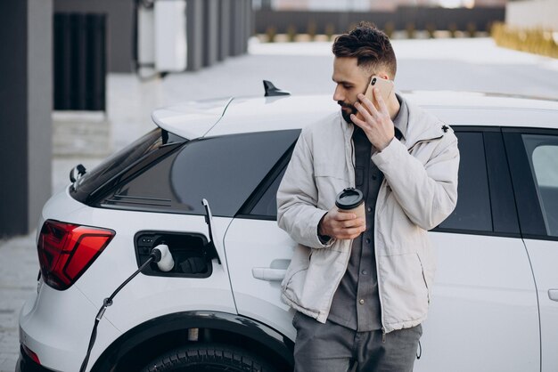 Uomo che carica un'auto elettrica vicino alla casa