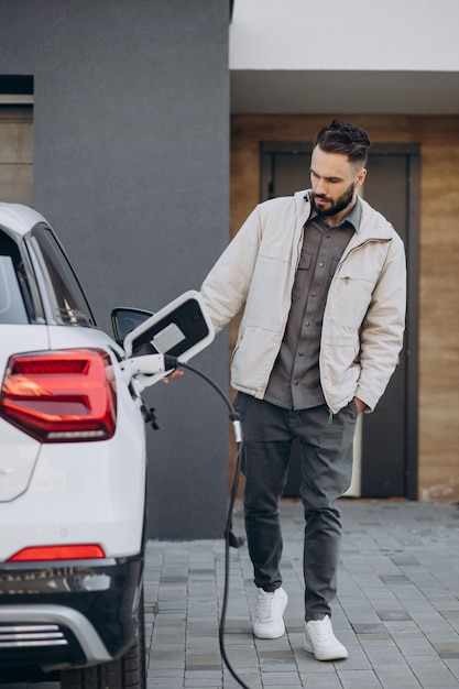 Uomo che carica un'auto elettrica vicino alla casa