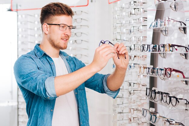 Uomo che cerca nuovi occhiali all&#39;optometrista