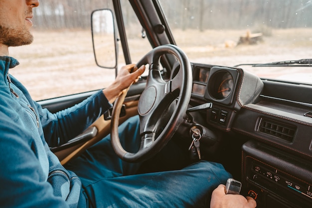 Uomo che conduce l'automobile del suv dalla strada della traccia della foresta