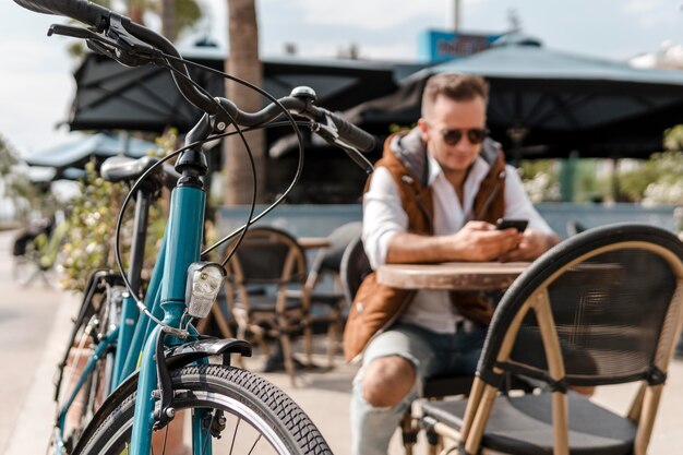 Uomo che controlla il suo telefono accanto a una bicicletta