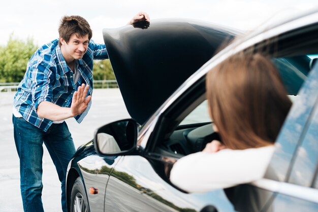 Uomo che controlla motore e donna che si siedono in automobile