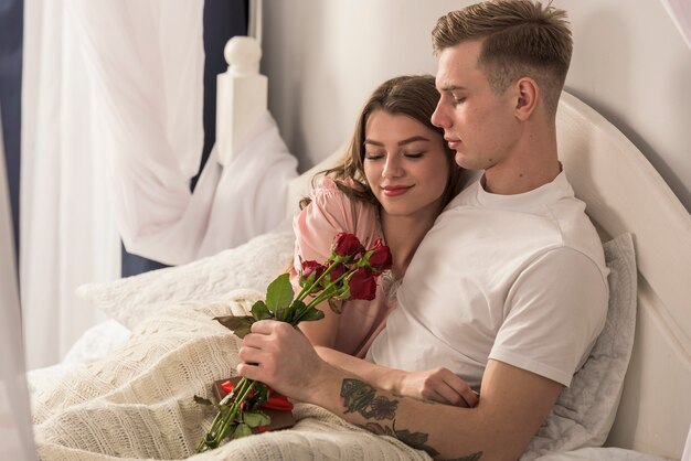 Uomo che dà le rose rosse alla donna a letto