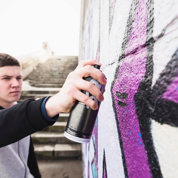 Uomo che disegna graffiti al muro di strada