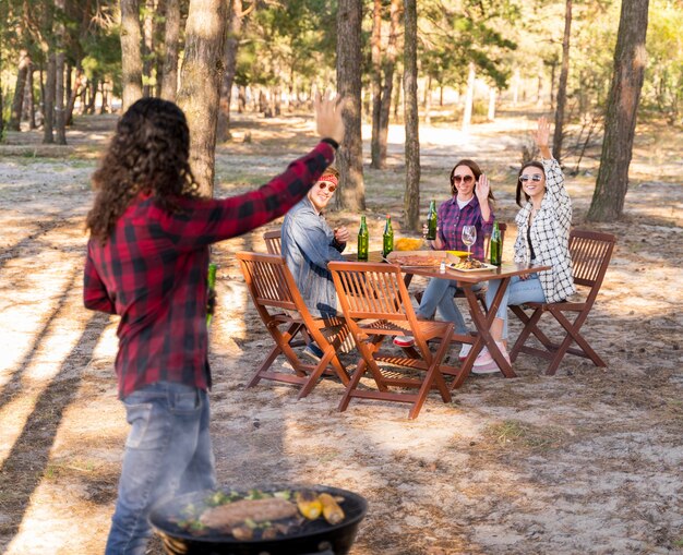 Uomo che esulta con gli amici mentre si tiene la birra e si mangia un barbecue