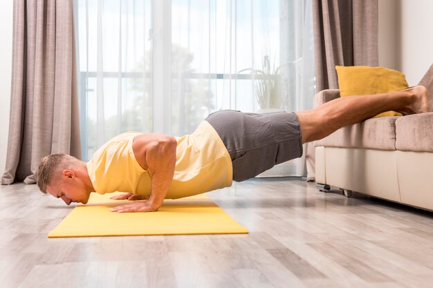 Uomo che fa fitness a casa utilizzando il divano