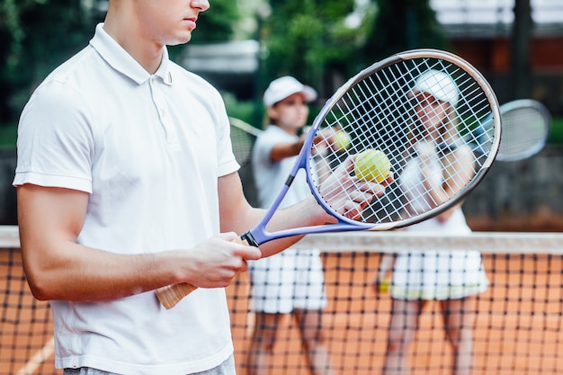 Uomo che fa oscillare una racchetta da tennis con entrambe le mani per fare un tiro forte. Allenati la sera prima di una partita.