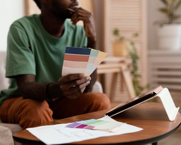 Uomo che fa un piano utilizzando tablet per ridipingere la casa