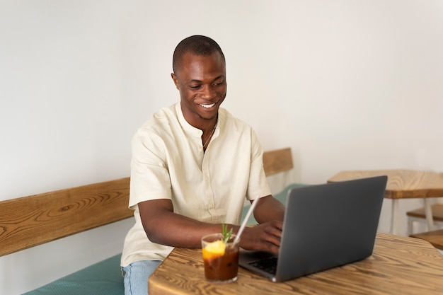 Uomo che fa una pausa caffè ghiacciata mentre utilizza il laptop