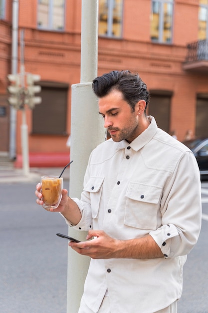 Uomo che fa una pausa caffè ghiacciata mentre utilizza lo smartphone