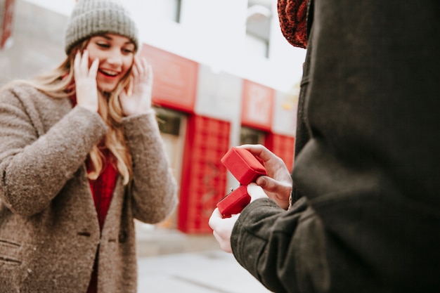 Uomo che fa una proposta alla donna stupita