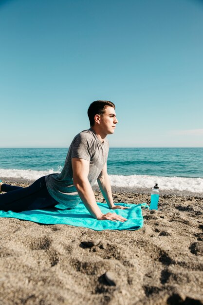 Uomo che fa yoga in spiaggia
