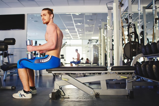 Uomo che flette i muscoli con manubri