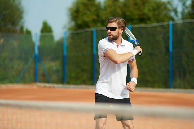 Uomo che gioca a tennis in giornata di sole