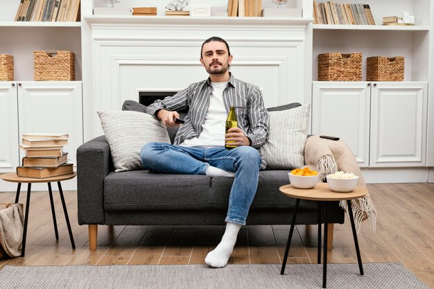 Uomo che gode di una birra e guarda la tv al chiuso