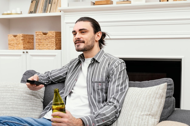 Uomo che gode di una birra e guarda la tv