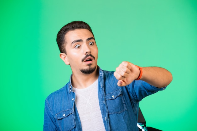 Uomo che guarda al suo orologio, controlla il tempo e sorpreso.