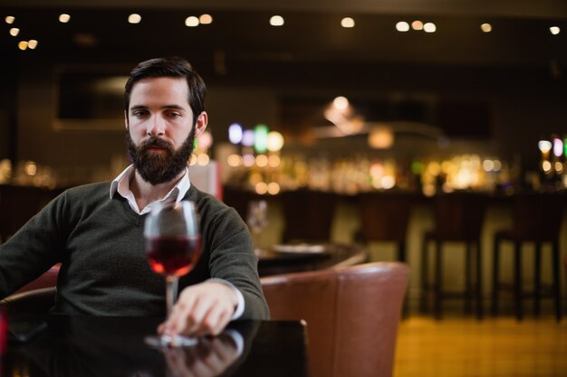 Uomo che guarda il bicchiere di vino rosso