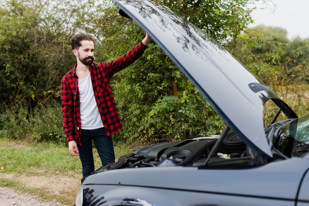 Uomo che guarda il motore dell'auto