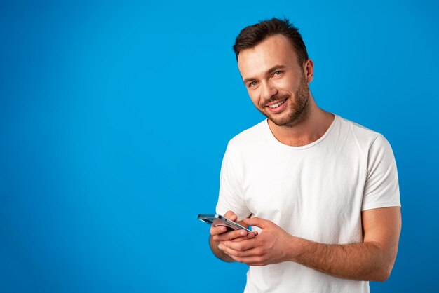 Uomo che guarda il telefono in piedi isolato su sfondo blu