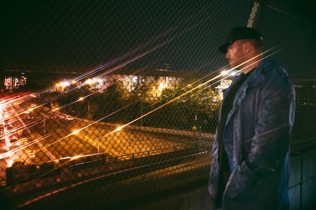 Uomo che guarda l'autostrada trafficata di notte sul ponte