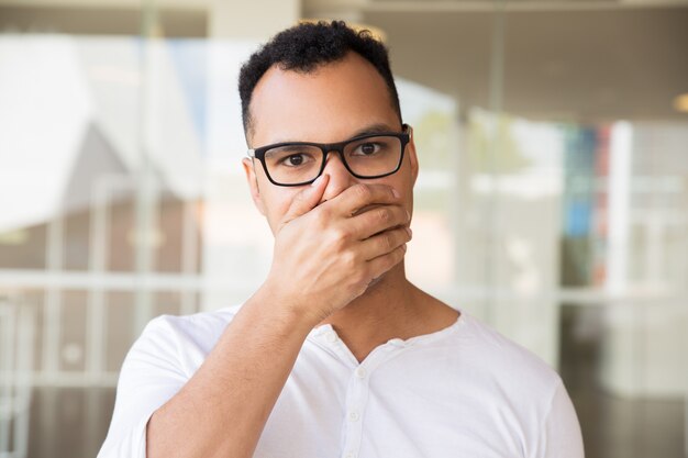 Uomo che guarda l&#39;obbiettivo, che chiude la bocca con la mano, sembra scioccato