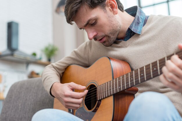 Uomo che guarda la chitarra e suona