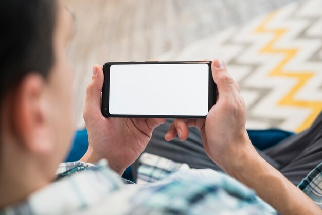 Uomo che guarda smartphone sul divano