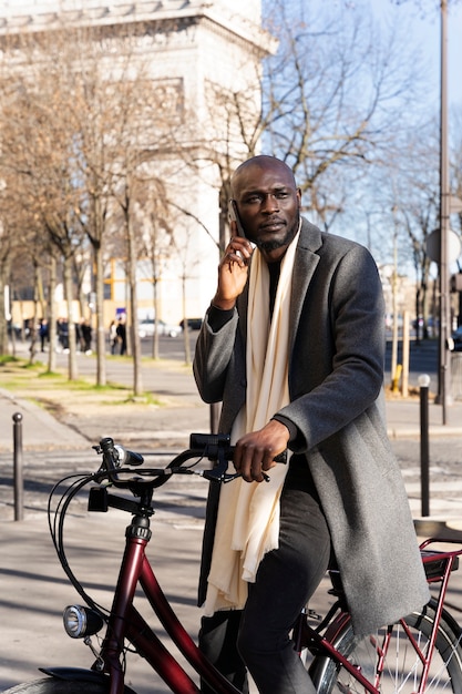 Uomo che guida la bici e parla sullo smartphone in città in Francia
