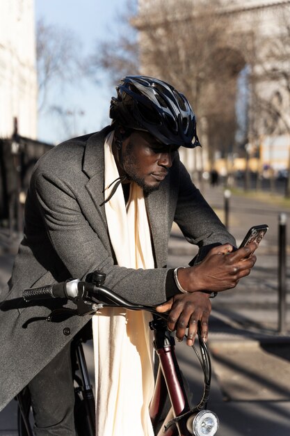 Uomo che guida la bici e utilizza lo smartphone in città in Francia