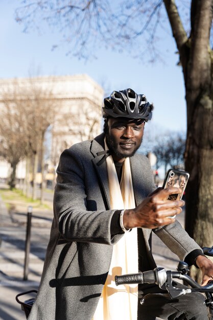 Uomo che guida la bici e utilizza lo smartphone in città in Francia