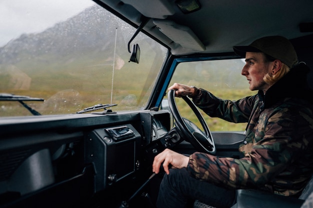 Uomo che guida un vecchio SUV nelle Highlands