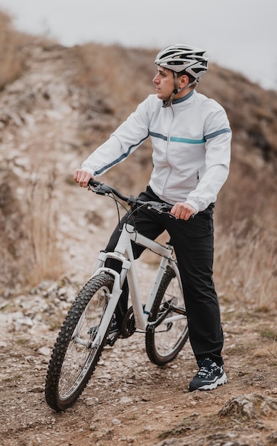 Uomo che guida una bicicletta in una giornata fredda e guarda lontano