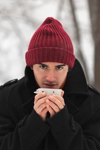 Uomo che indossa cappello rosso sorseggiando da una tazza di tè