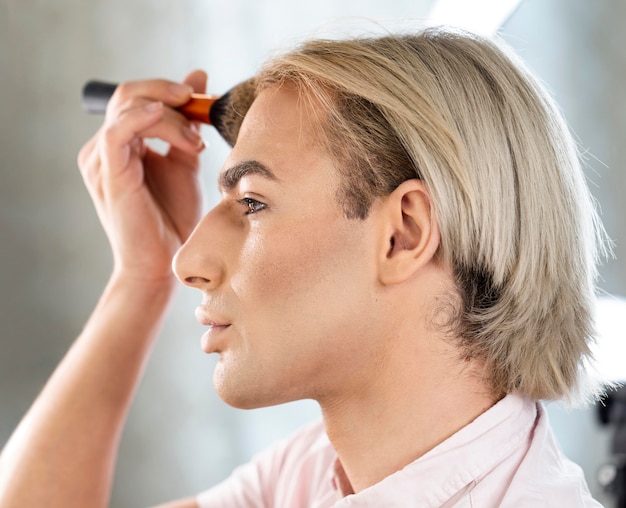 Uomo che indossa il trucco utilizzando il pennello