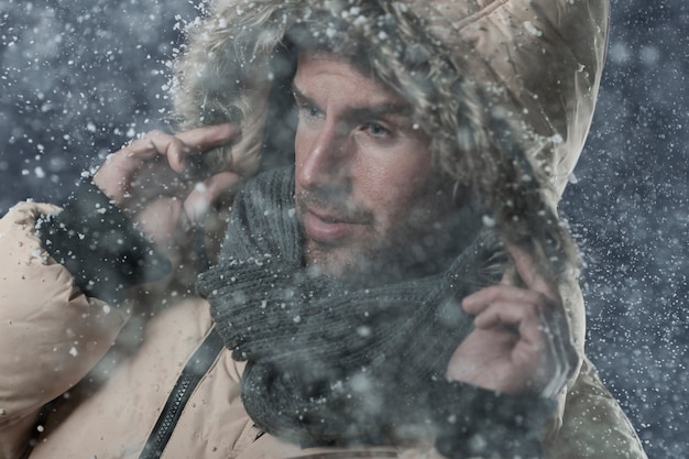 uomo che indossa una giacca invernale mentre nevica